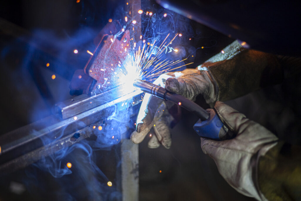 Alt text: Sparks fly in a close-up shot of a welder at work.
