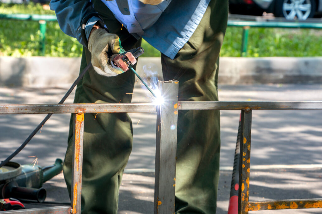A welder is working in the field with thin metal.