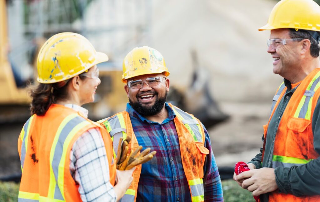 A group of construction workers discuss an industrial contracting project on a worksite.